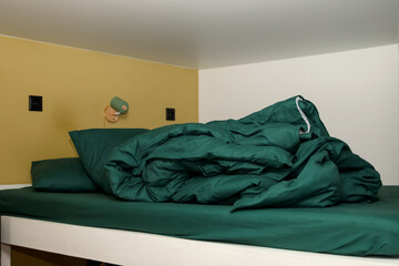 a bunk bed with a green, crumpled, and messy blanket. a simple and a cozy design. messy bunk bed cozy room. crumpled green blanket lazy morning
