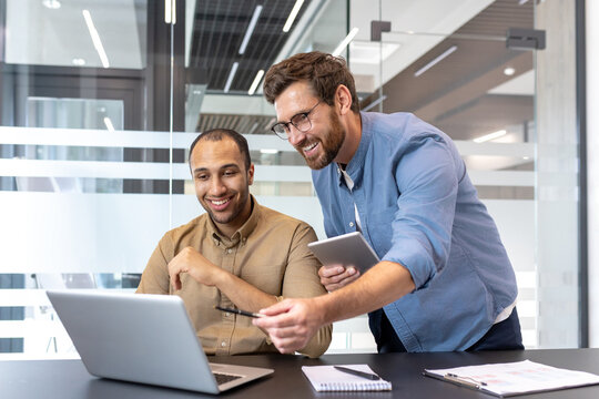 Two coworkers collaborating on a project in a modern office environment - Powered by Adobe
