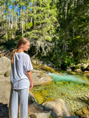 Woman enjoying mountain stream along hiking trail in scenic valley. Concept: relaxation, freedom, connection with nature.