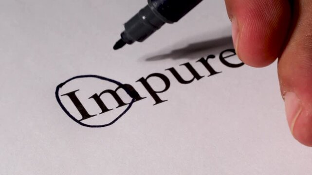 Close-up of a hand holding a pen editing text on paper, removing the prefix &ldquo;im&rdquo; from the word &ldquo;impure&rdquo; to reveal &ldquo;pure,&rdquo; symbolizing clarity, positivity, and transformation.
