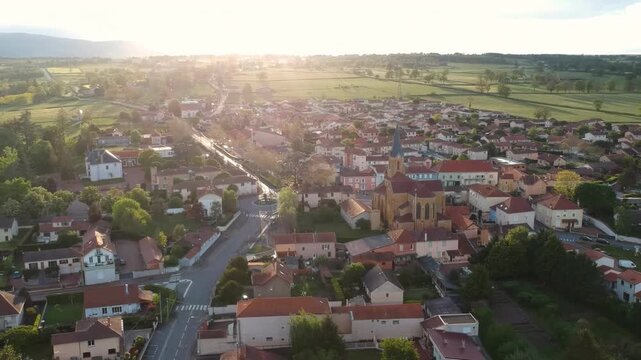 Aerial 4K drone view of picturesque French village with church at sunset.