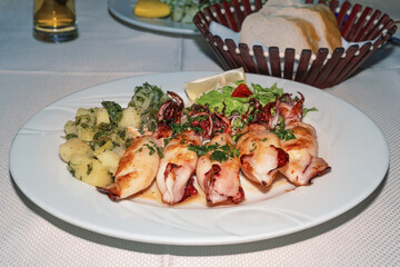 Grilled squid with vegetables and potatoes on a table in a restaurant