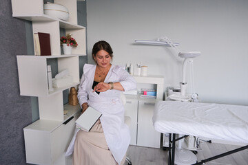cosmetologist sitting reading a book during a coffee break and checking time