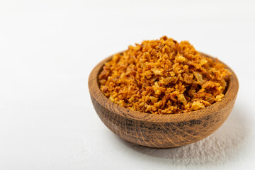 Crispy fried onions in a bowl on a wooden table. Roasted Onions. Seasoning for dishes. Spices. Salad dressing. Space for text. Copy space