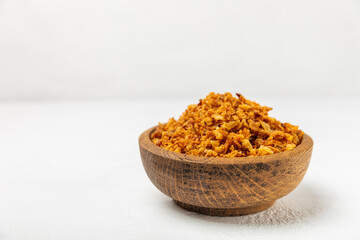 Crispy fried onions in a bowl on a wooden table. Roasted Onions. Seasoning for dishes. Spices. Salad dressing. Space for text. Copy space