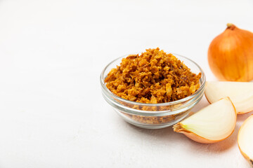 Crispy fried onions in a bowl on a wooden table. Roasted Onions. Seasoning for dishes. Spices. Salad dressing. Space for text. Copy space