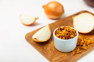 Crispy fried onions in a bowl on a wooden table. Roasted Onions. Seasoning for dishes. Spices. Salad dressing. Space for text. Copy space