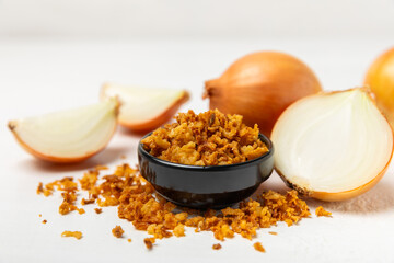 Crispy fried onions in a bowl on a wooden table. Roasted Onions. Seasoning for dishes. Spices. Salad dressing. Space for text. Copy space