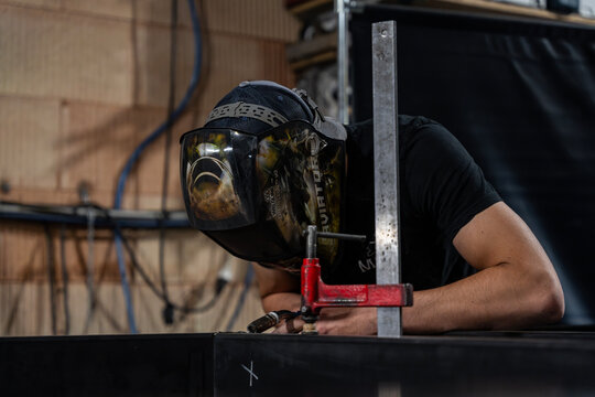 M&eacute;tallier portant un casque de protection, manipulant une pi&egrave;ce m&eacute;tallique sur l&rsquo;&eacute;tabli de son atelier.