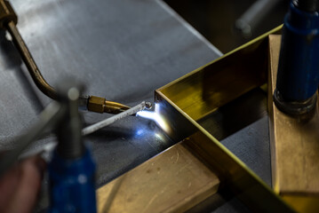 Chalumeau en action réalisant une soudure sur une pièce métallique posée sur l’établi d’atelier.