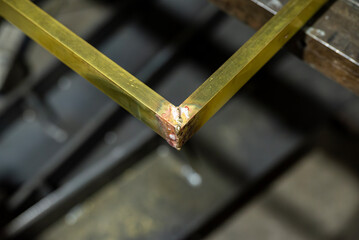 Pièce métallique posée sur l’établi d’un métalier, avec une soudure fraîchement réalisée encore visible.