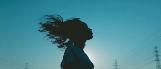 The silhouette of a woman enjoying the breeze at sunset against a vivid sky