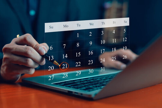 Businessman pointing pen at digital calendar on laptop with date circled, concept of schedule planning, appointment reminder, time management, business meeting, productivity.