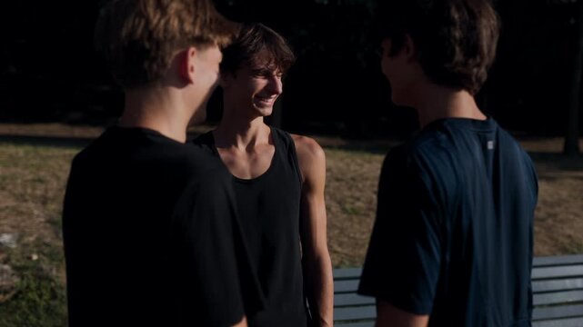 Three teen boys talking and hanging out outdoors at sunset by the water