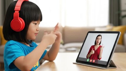 Girl with red headphones uses sign language on a tablet video call - Powered by Adobe