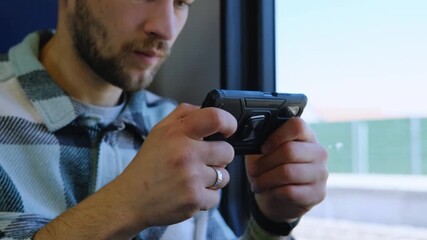 Man playing on smartphone while sitting on train seat, modern travel with technology. Solo travel concept - Powered by Adobe