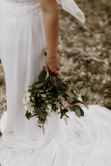 Bride Holding Greenery Wedding Bouquet in White Lace Dress