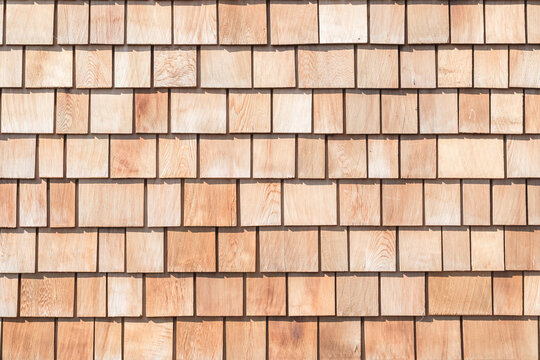 Wooden shingle roof background of new red brown cedar shake wood tile siding row panel pattern made of larch conifer tree in building construction for house design industry
