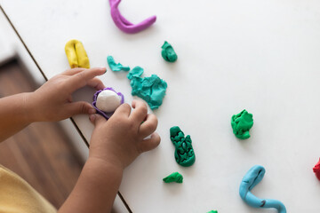 A child is playing with clay on a table. The clay is. The scene is playful and creative