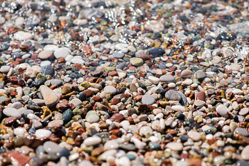 Sea colored pebbles on the beach, clear sea water