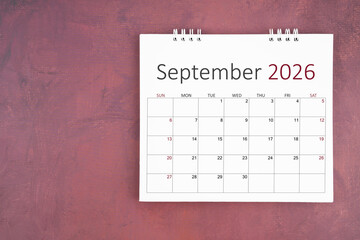 September 2026 desk calendar on red cement wall background. Page of annual monthly calendar for plan.