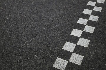 A close-up displays a textured asphalt surface adorned with white, checkered square pattern design.