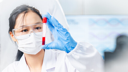 Female scientist wearing protective mask and gloves examining a blood sample in a test tube inside a modern laboratory, representing healthcare research, diagnostics, and biotechnology.
