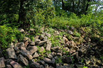 a sloped area along a creek, near a hiking trail. riprap used for erosion control and stabilization. environment background.