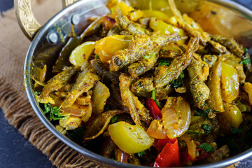 Traditional Bengali mourola fish curry cooked with green tomato, authentic homemade small fish...