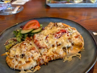 Delicious flatbread pizza with melted cheese tomatoes and salad on a rustic plate