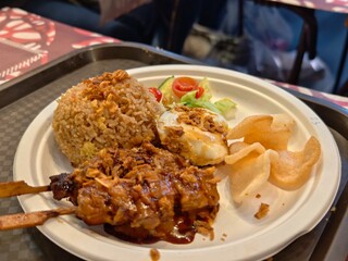 Indonesian satay ayam with rice egg and crackers on a plate ready to eat