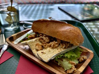 Savor the moment with a brie and walnut sandwich on a wooden tray at a cafe
