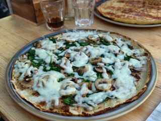 Delicious mushroom and spinach pizza with melted mozzarella cheese on a wooden table