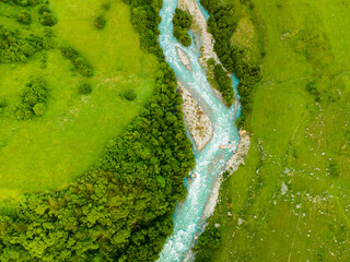 River with green trees and fresh green grass. Aerial top down view.