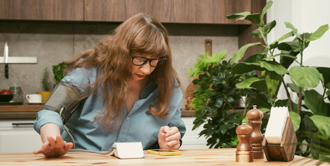 Beautiful elderly woman looks at the tonometer screen measuring blood pressure wit in stylish modern apartment