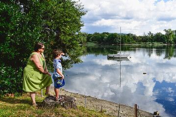 Obraz premium Mum and son enjoy a day by the tranquil lakeside in summer