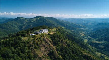 Obraz premium Stunning aerial view of a mountain lodge surrounded by lush green hills in the daytime