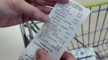 A person is holding a receipt for a shopping cart - Powered by Adobe
