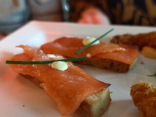 Delicious smoked salmon canapés with cream cheese and chives on a white plate