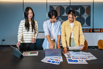 This dynamic Asian business team of professionals engages in a collaborative meeting, analyzing documents and strategizing for financial projects in a contemporary office environment.