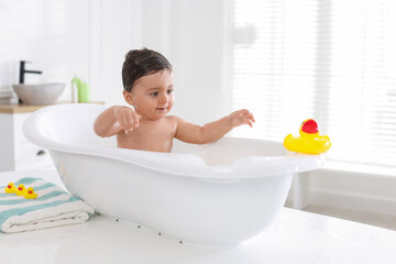 Naklejka premium Cute little baby bathing in tub at home