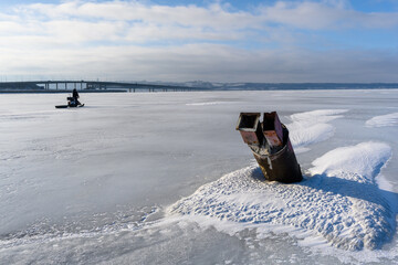A fisherman looks into the distance and rides a snowmobile on the frozen Volga River.
