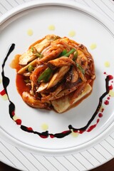 Assorted mushrooms stir-fried and served over grilled tofu, a hearty Korean dish prepared by master chef Hanshunseop. Photographed in Korea.