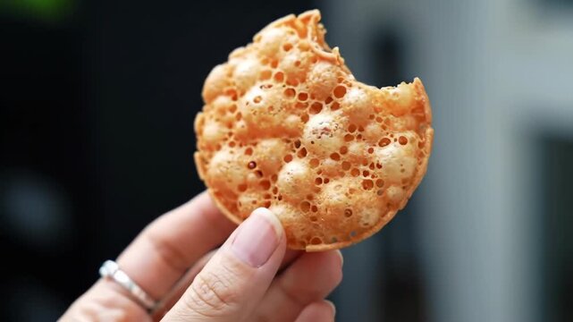Crispy golden cookie in hand, a delicious treat missing a bite