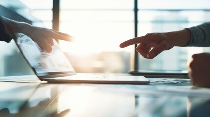 The laptop illuminated by two reaching hands in a collaborative work environment.