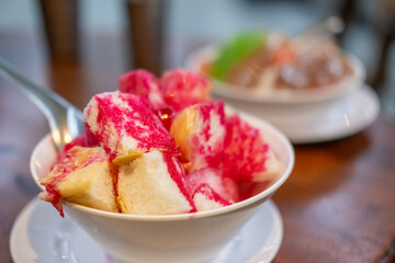 Namkhaeng Sai or Wan Yen, a Thai shaved ice in a bowl with bread, topped with sweet syrup and condensed milk.
