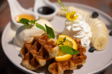 Waffle with vanilla ice cream served with sliced banana , whipped cream and sauce.