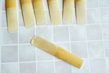 Close-up of multiple clarinet reeds made of natural cane arranged on a tiled background, essential woodwind instrument accessory for musicians and music practice