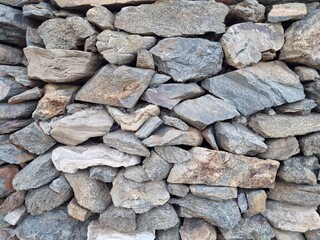Rustic stone wall texture made of stacked natural rocks. Perfect background for design, 3D modeling, architecture, interiors, exteriors, game assets, and creative projects.