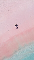 Fototapeta premium Top view of a relaxed young Asian woman laying on the pink sand at Pink Beach, Labuan Bajo.